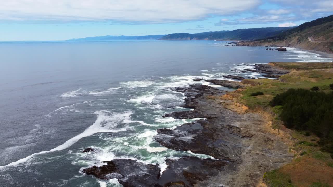 4K 30FPS Aerial Footage Oregon Coast - Flying drone shot of the California Oregon border coastline- White capped pacific ocean waves crashing against the rocky coast and US Route 101 in the background