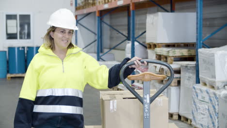 smiling female worker pulling trolley with boxes in stock