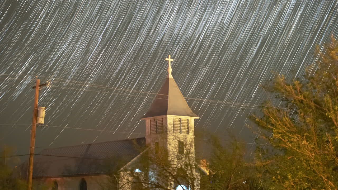 Stars trail in to streaks over a small church steeple - Astro Time lapse