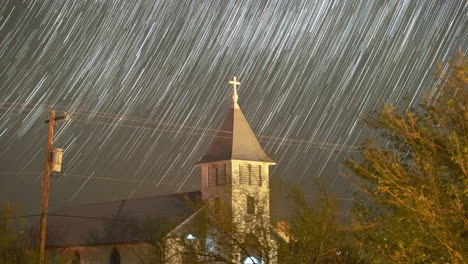stars trail in to streaks over a small church steeple - astro time lapse