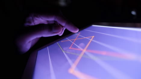 hand on tablet screen displaying graphs at night