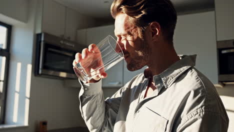 man drinking water in a kitchen