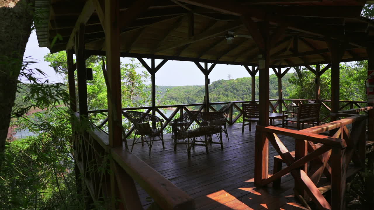 Slow motion reveal of Jungle Cabin Lodge’s outdoor dehor shows a wooden deck over the Paraná River, surrounded by lush jungle in Misiones, Argentina—blending rustic architecture with natural immersion