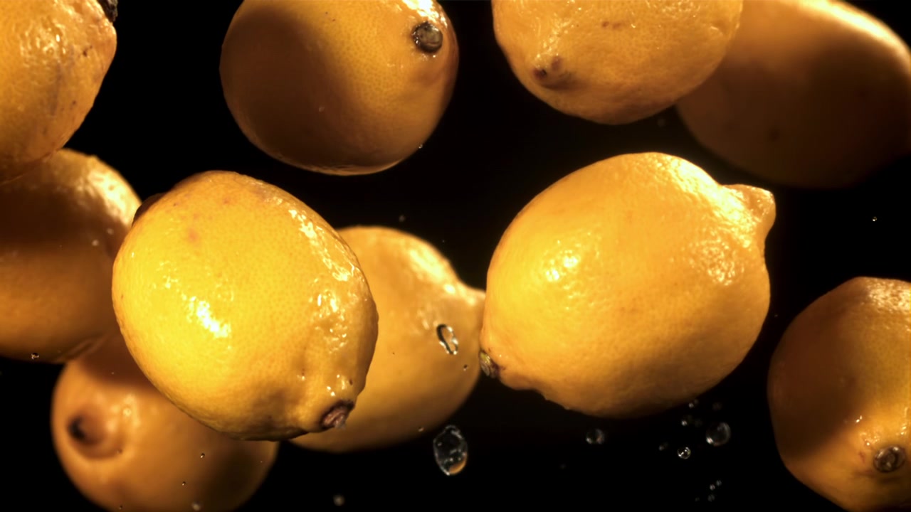 Limoni gialli freschi che galleggiano con goccioline d'acqua al rallentatore
