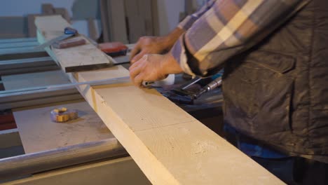 carpenter cuts timber with handsaw in carpentry workshop.