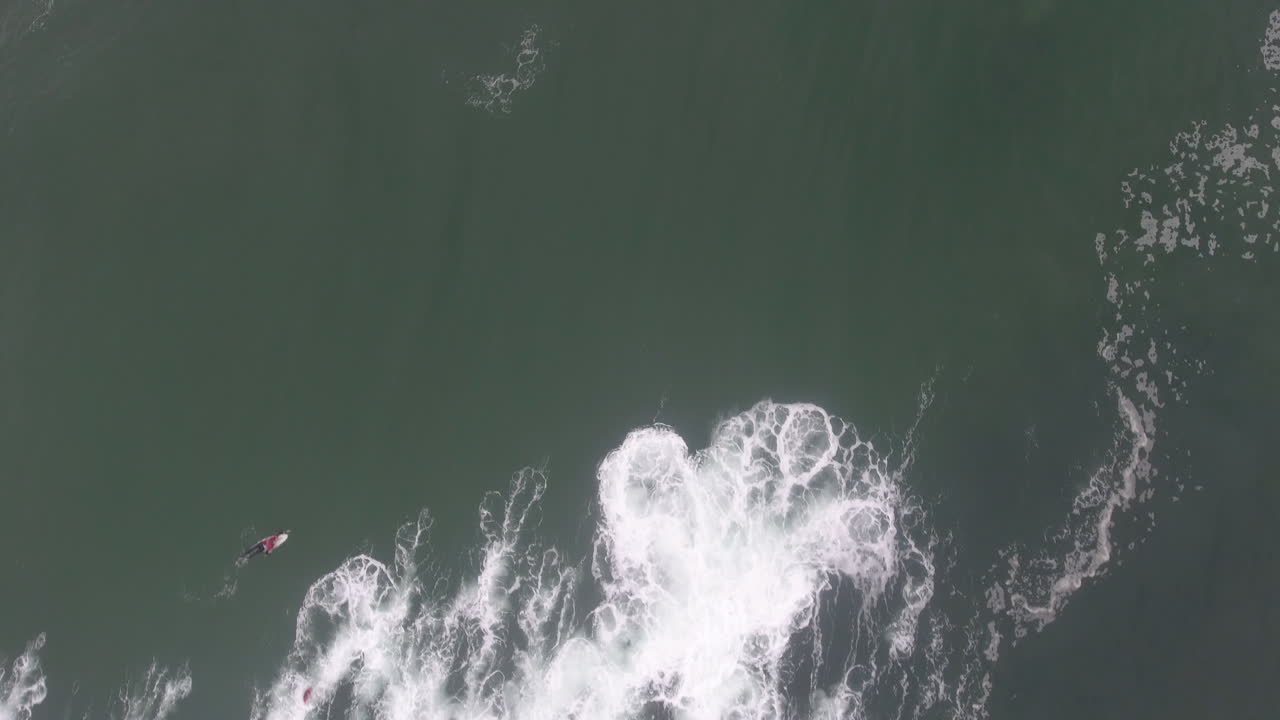 남아프리카 공화국의 커피 베이에서 서핑하는 서퍼 위로 날아가는 공중 액션 시네마틱