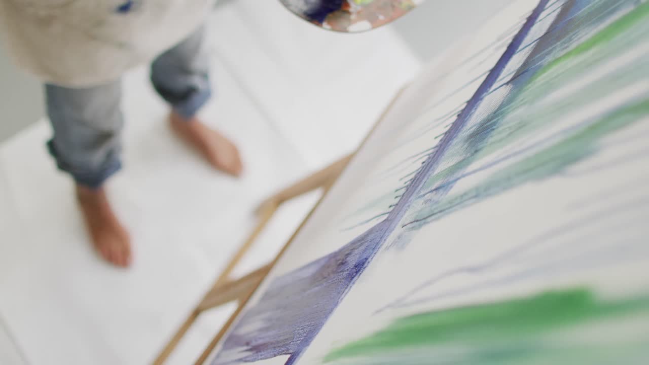 video de las piernas de una artista biracial pintando en un estudio