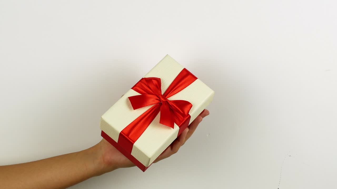 mujer con la mano sosteniendo un regalo para feliz navidad. regalo de año nuevo y navidad en cajas brillantes con un arco sorpresa. video en 4k de un primer plano de una caja de regalos.