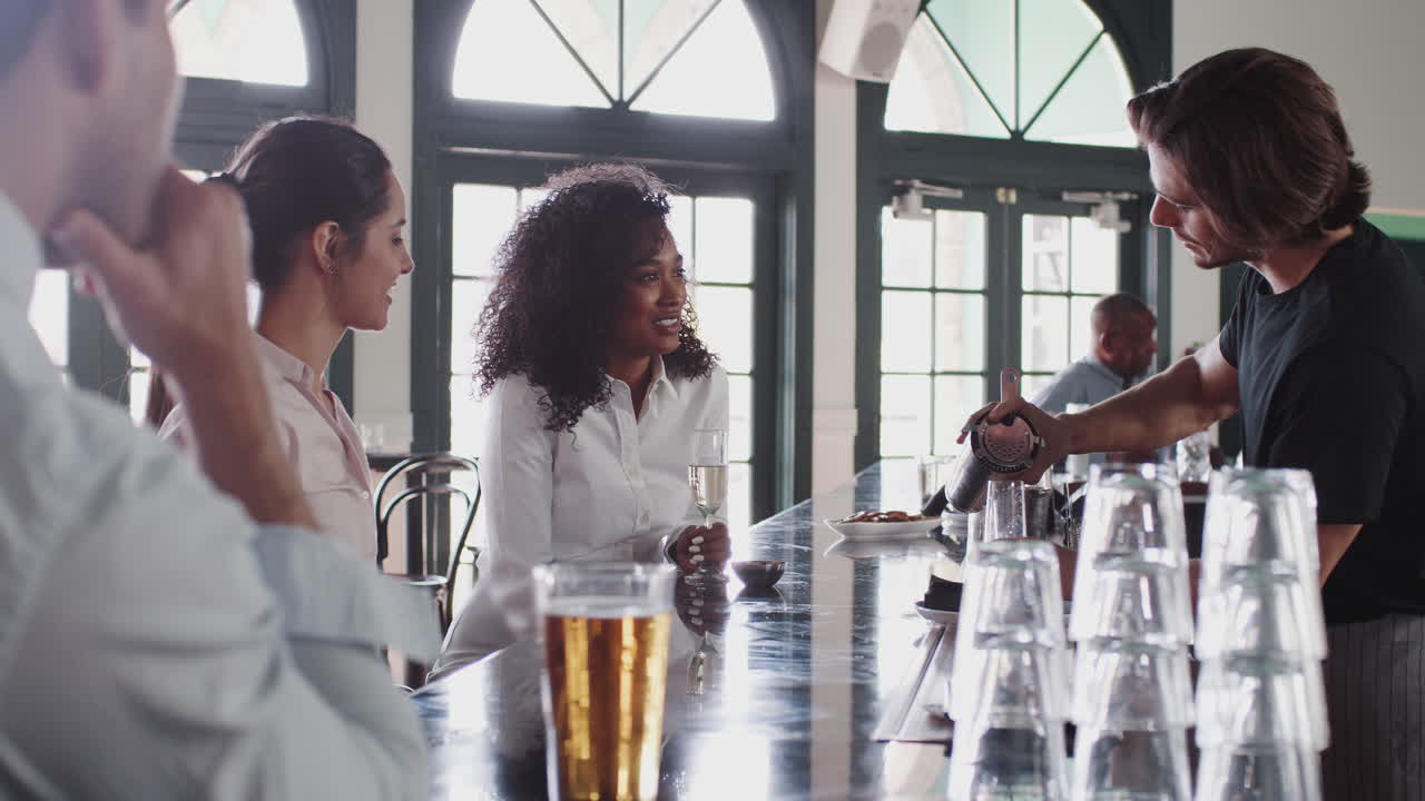 barman sirviendo a dos mujeres de negocios que se reúnen para tomar bebidas después del trabajo