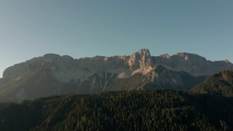 Flying-over-the-lush,-green-forest-of-the-Zell-Pfarre-Valley-in-Austria-with-the-rocky-mountain-in-the-distance---Aerial-shot