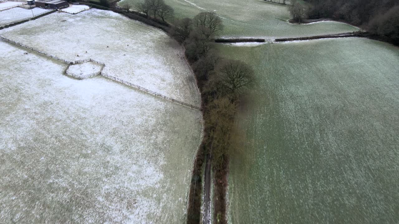 A 4k Aerial drone shot flying over a frozen winter countryside path