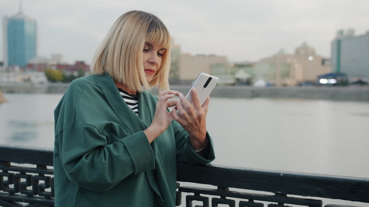 Woman using smartphone on a bridge