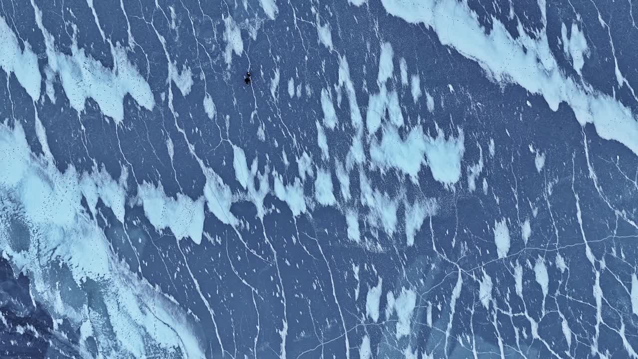 Paar erkundet weite gefrorene Meeresoberfläche mit Eisformationen, Luftbild-Draufsicht.