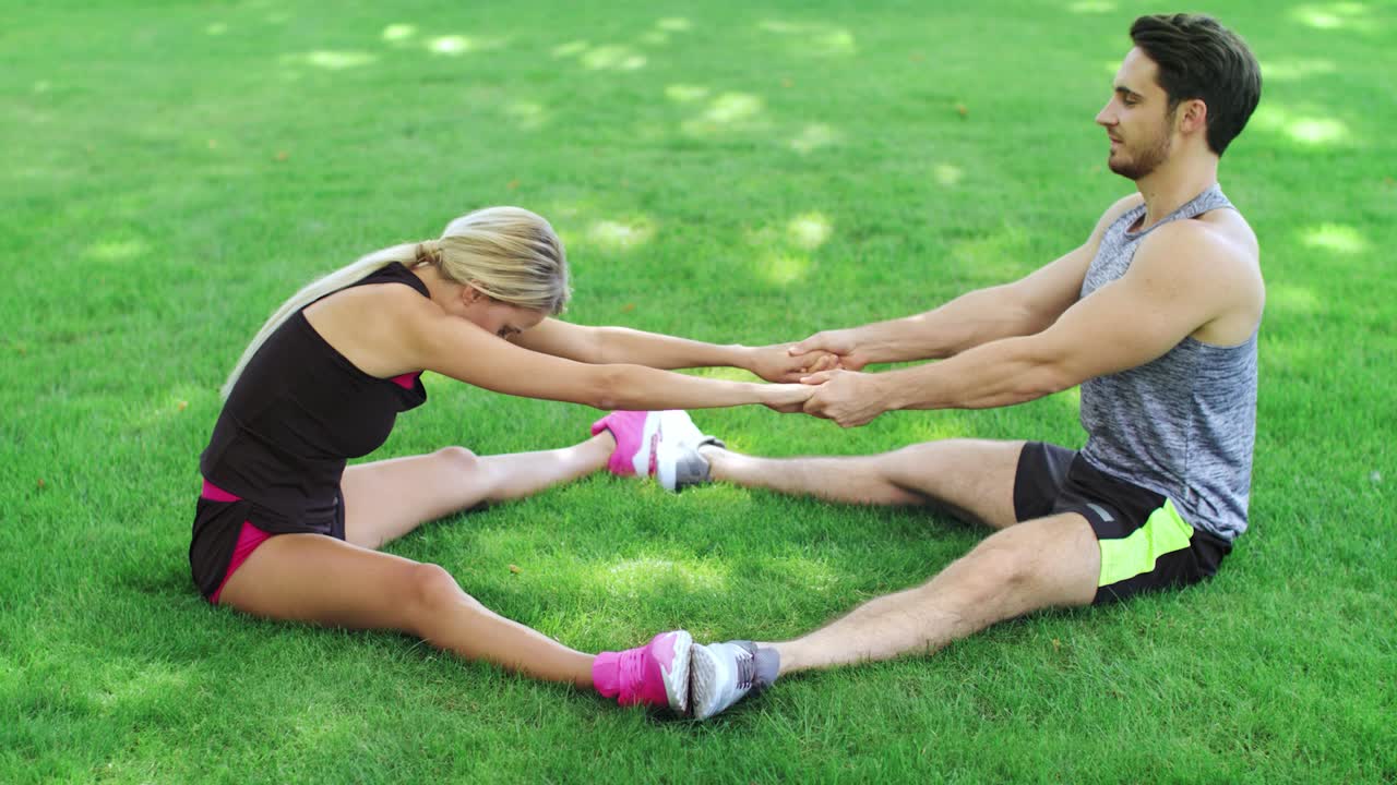 entrenador de fitness ayuda a la mujer estirando las piernas en el entrenamiento de calentamiento en el parque