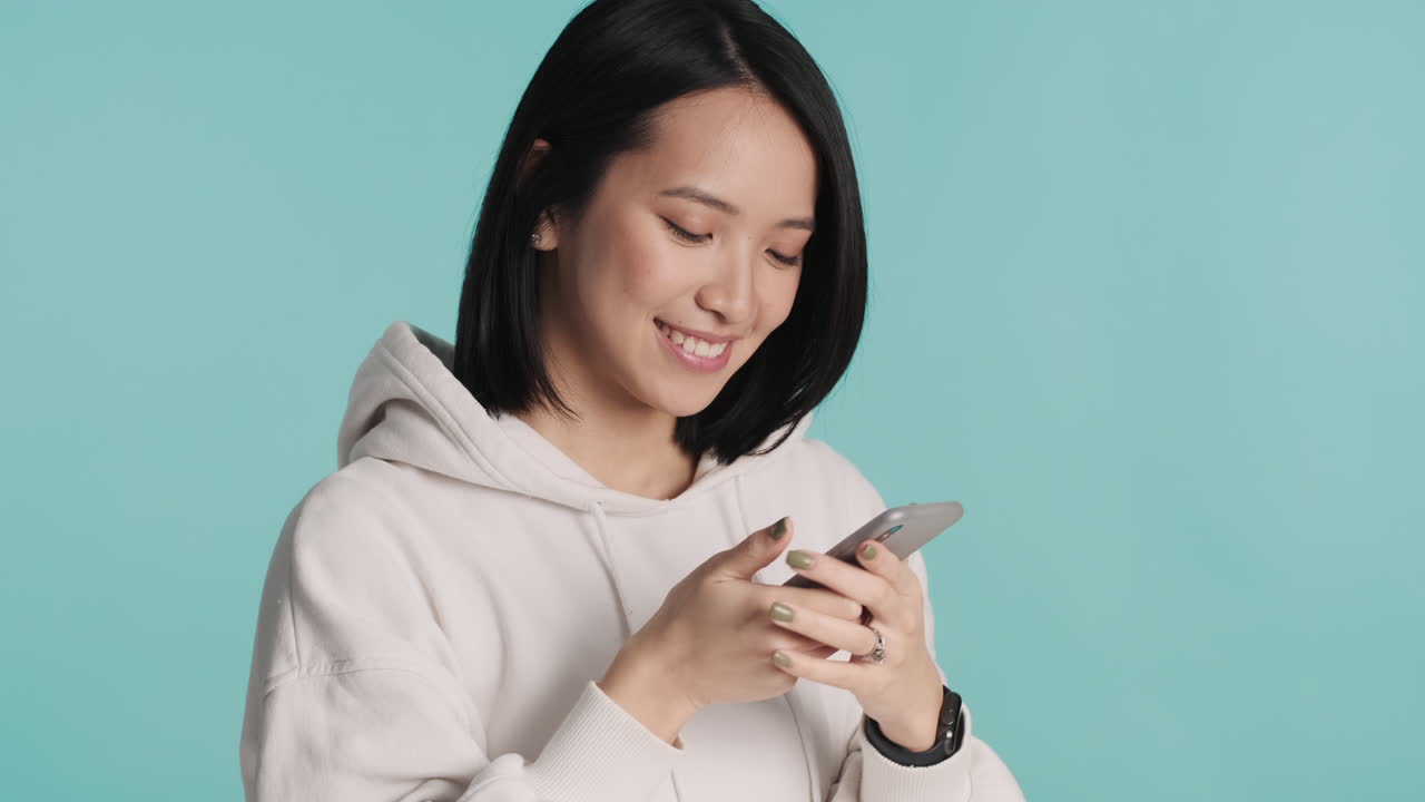 Asian woman taking selfie on smartphone.