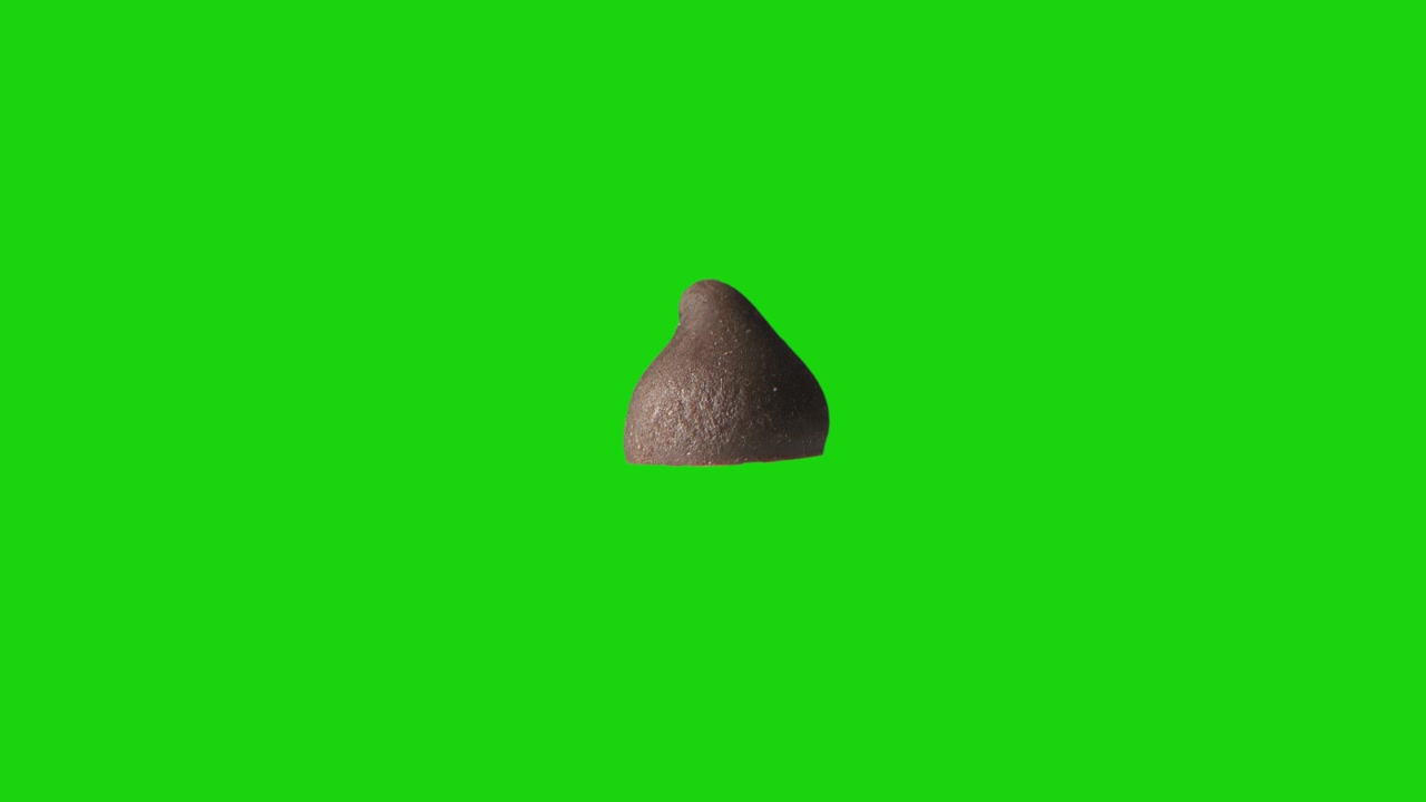 Goccia di cioccolato isolata e che ruota su sfondo chroma key verde. Un pezzo di cioccolato al latte ricco, dolce e gustoso che gira