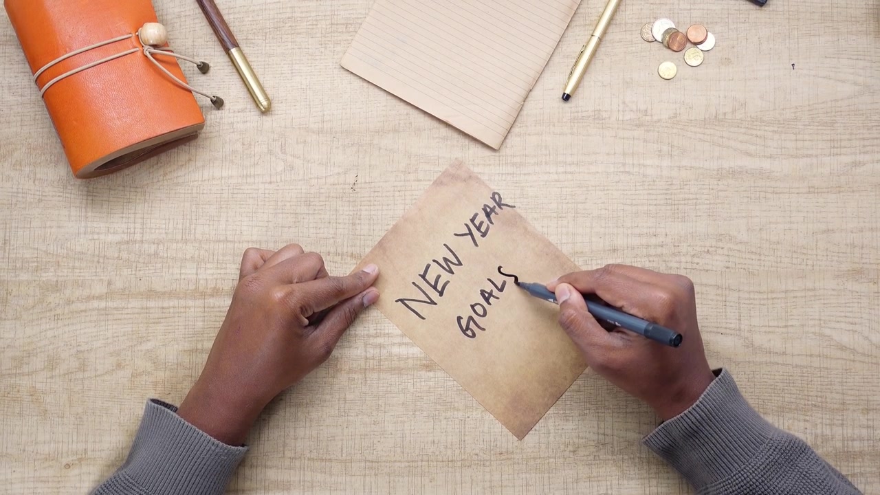 Person Writing New Year Goals on Vintage Paper