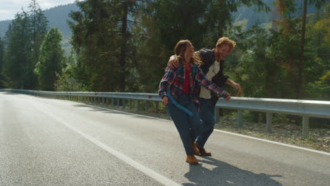 Hipsters-Caminando-Divirtiéndose-En-Las-Montañas-Haciendo-Autostop.-Turistas-Caminando-Carretera-Carretera