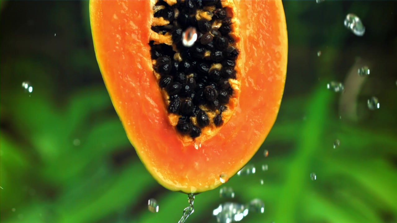Metà di papaya fresca con gocce d'acqua al rallentatore