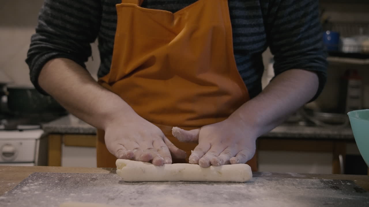 Close-Up of Chef's Hands Rolling Dough on a Floured Board