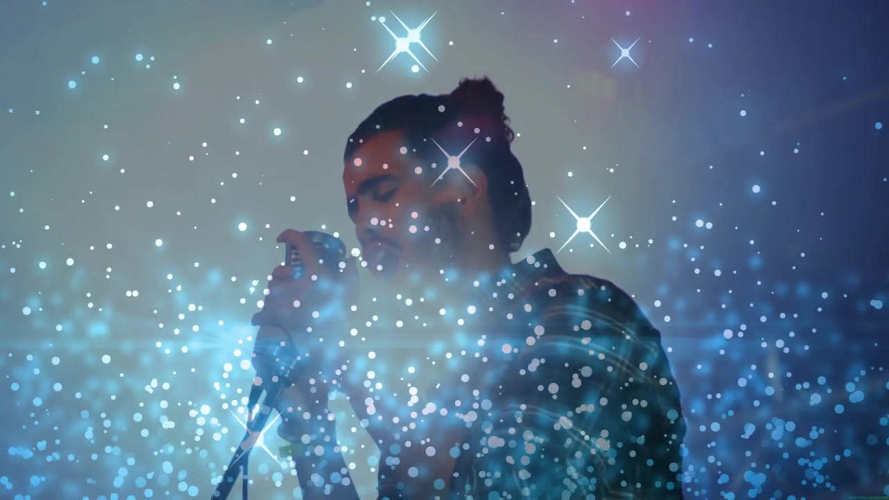 Vocalista masculino cantando em microfone retrô, com sobreposição de bokeh azul crescendo e escondendo o rosto para a música