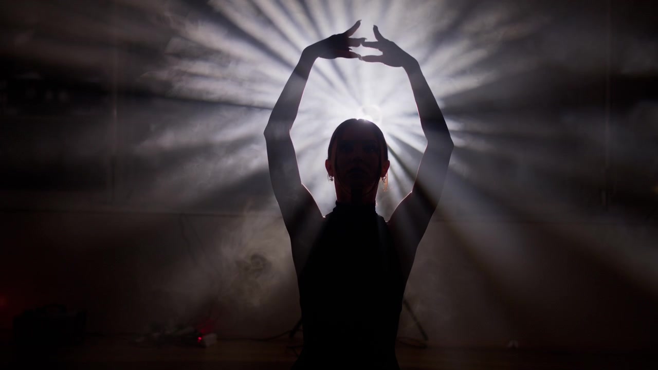 Silhueta misteriosa de uma dançarina executando uma dança contemporânea em um estúdio escuro e esfumaçado