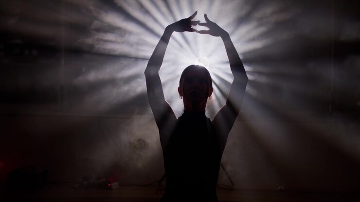 Silhueta misteriosa de uma dançarina executando uma dança contemporânea em um estúdio escuro e esfumaçado
