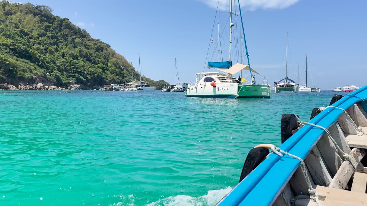 A boat navigates turquoise waters in Chalong Bay, Phuket, under clear skies, capturing serene coastal scenery