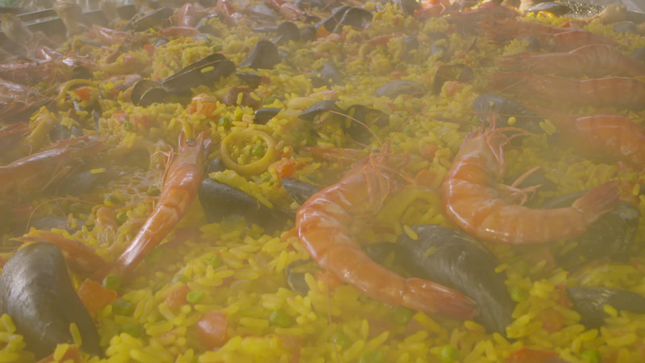 이 요리에 새우와 홍합 같은 재료가 내려다보이는 빠에야 팬의 클로즈업 샷에는 닭고기와 오징어 또는 오징어도 약간 있습니다