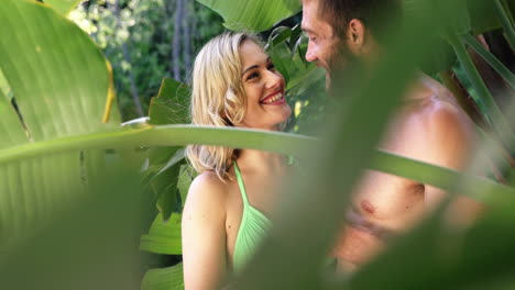 cute couple looking each other in the middle of palm tree