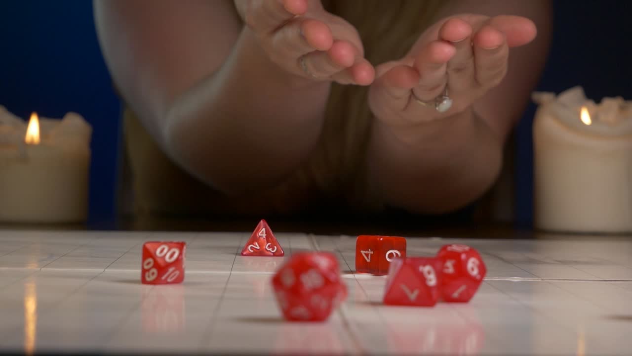 mujer tira dados rojos de rpg a través de la alfombra de juego con velas encendidas