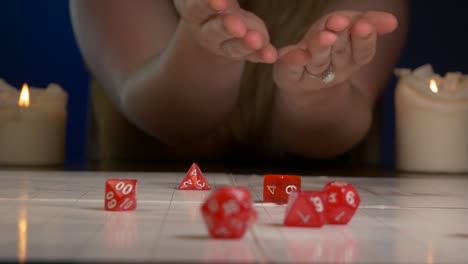 Woman-Rolls-Red-RPG-Dice-Across-Game-Mat-with-Candles-Lit