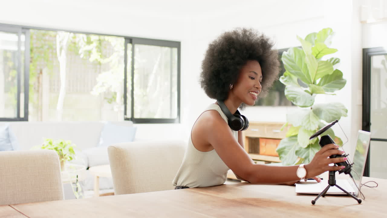 Working and podcasting from home, woman typing on laptop with headphones around neck, copy space