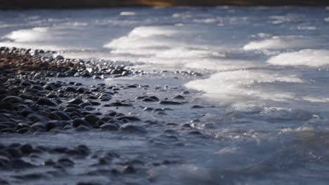 long waves roll slowly on the pebble beach in the long exposure video