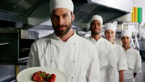 equipo de cocineros con uno presentando un plato