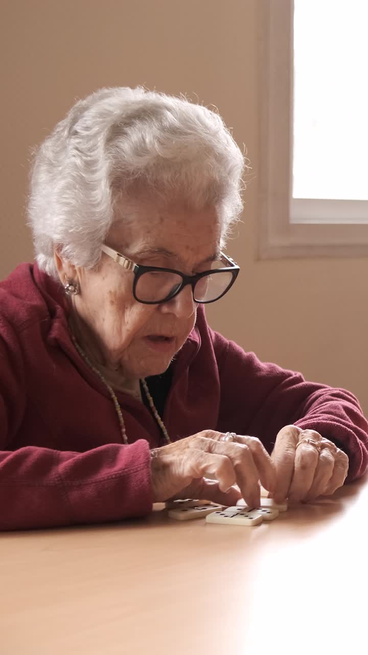 Senior friends playing dominoes at table in nursing home