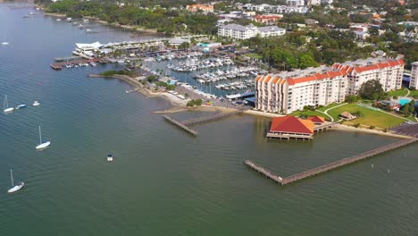 Drone-footage-over-downtown-Dunedin,-Florida-marina-with-boats-and-the-Gulf-of-Mexico-and-Tampa-Bay