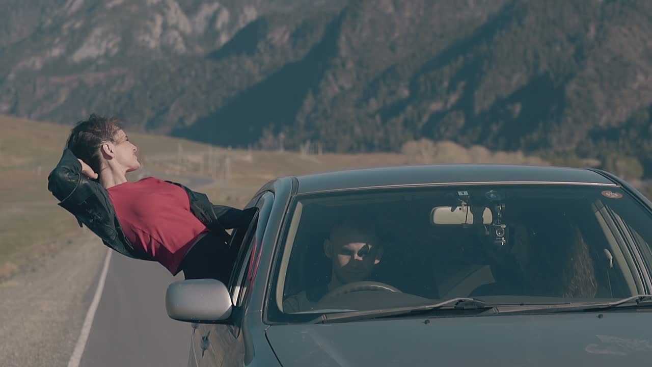 여자는 웃고 하늘을 바라보고 차에서 즐거움을 얻습니다.