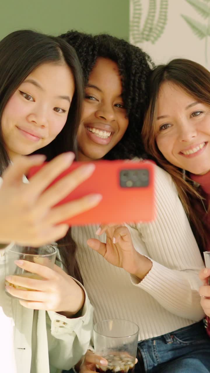 Multi-ethnic friends smiling taking a selfie indoors