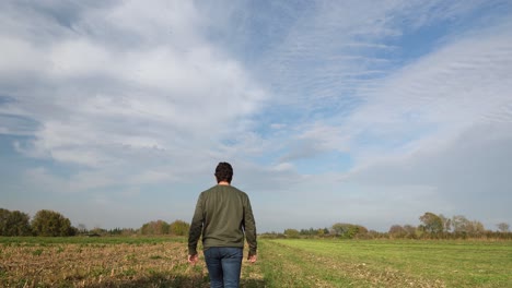 a young man walking into a field in a sunny day