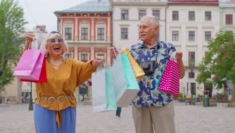 pareja de ancianos abuela abuelo turistas con bolsas después de comprar en el centro comercial durante el viernes negro