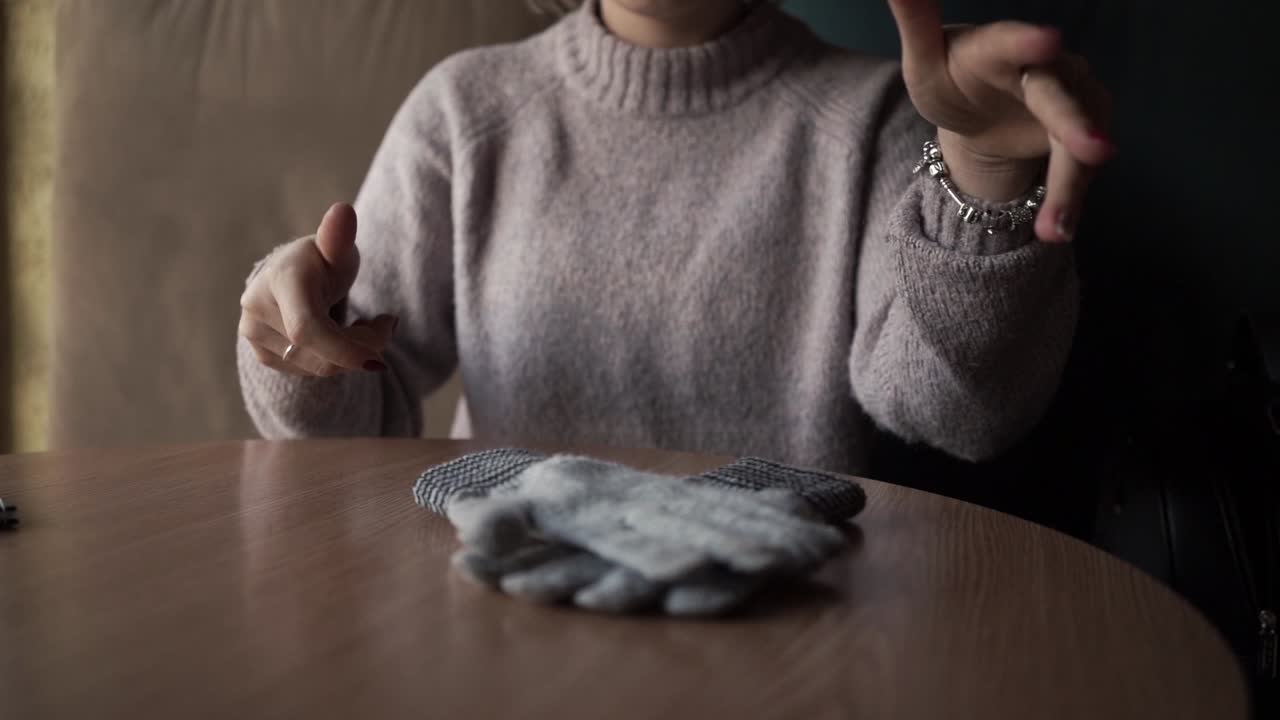 Gray winter gloves on the table. And the girl who holds them.