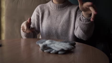 gray winter gloves on the table. and the girl who holds them.