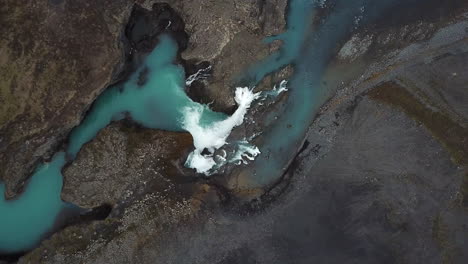 breathtaking nature of iceland, top view of glacial waterfall and canyon between volcanic hills, birdseye aerial