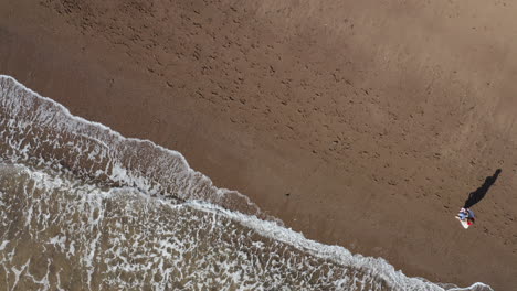 Drone-Shot-Of-Family-On-Vacation-With-Father-And-Children-Walking-Along-Beach-By-Breaking-Waves