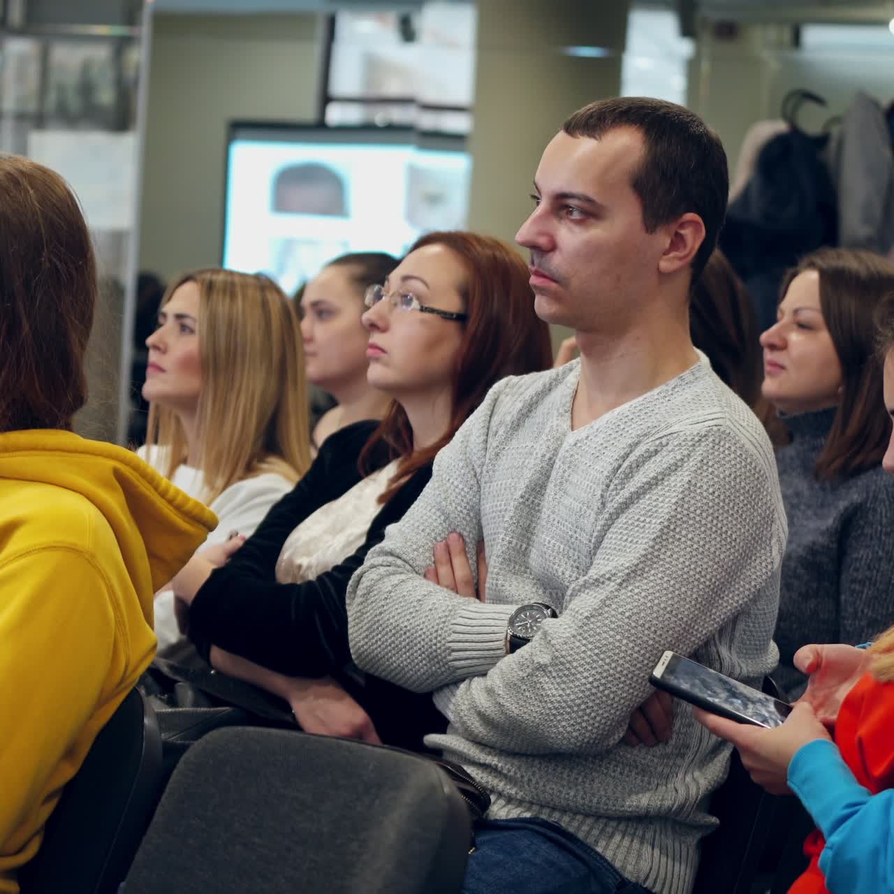 Adults sitting in the auditorium. People listening the lecture in the conference hall. Young listeners at public seminar.