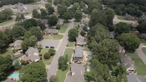 A drone zoom-in shot capturing a suburban neighborhood in the United States, showcasing tree-lined streets and residential houses. The greenery and -planned layout highlight the peacefulsuburban