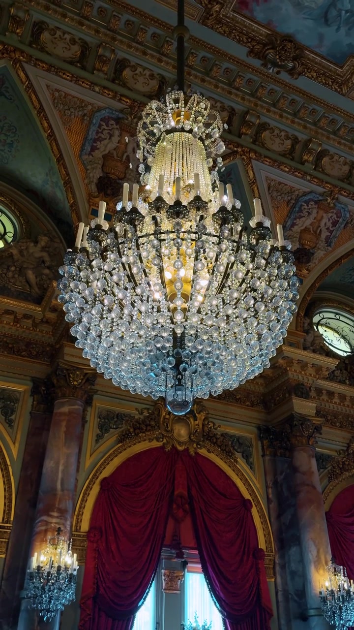 Boston, USA, 5 maggio 2025: Interno di una grande sala da ballo con lampadario di cristallo e tende di velluto rosso. Sala sontuosa con un grande lampadario di cristallo, colonne di marmo e tende drappeggiate di rosso intenso
