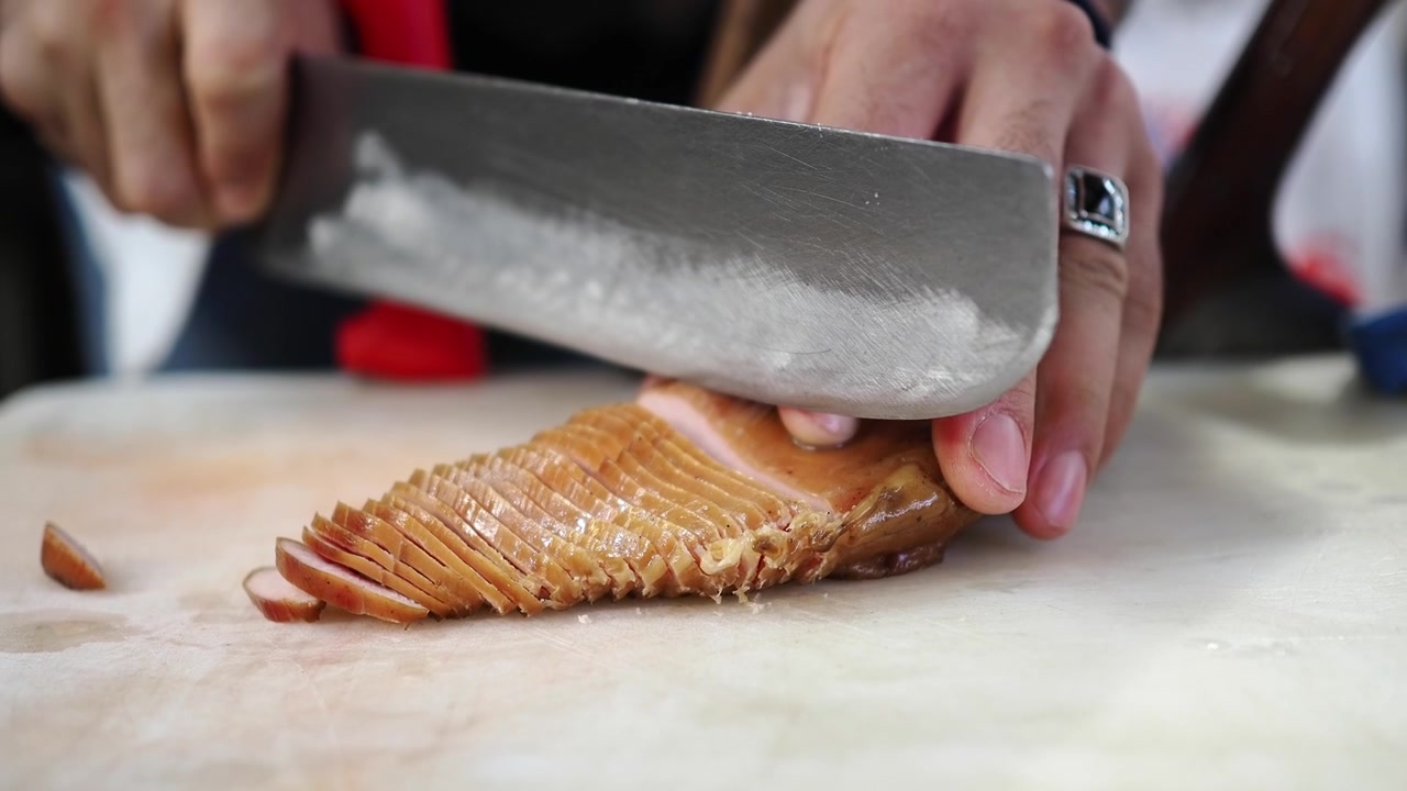 Chef che affetta carne affumicata su un tagliere di legno