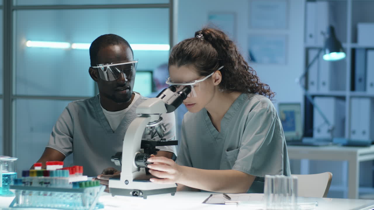 Multiethnic Scientists Working with Microscope in Lab